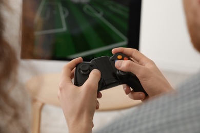 Photo of Young man playing video games at home, closeup