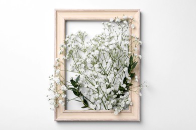 Photo of Wooden frame with beautiful gypsophila flowers and eucalyptus branches on white background