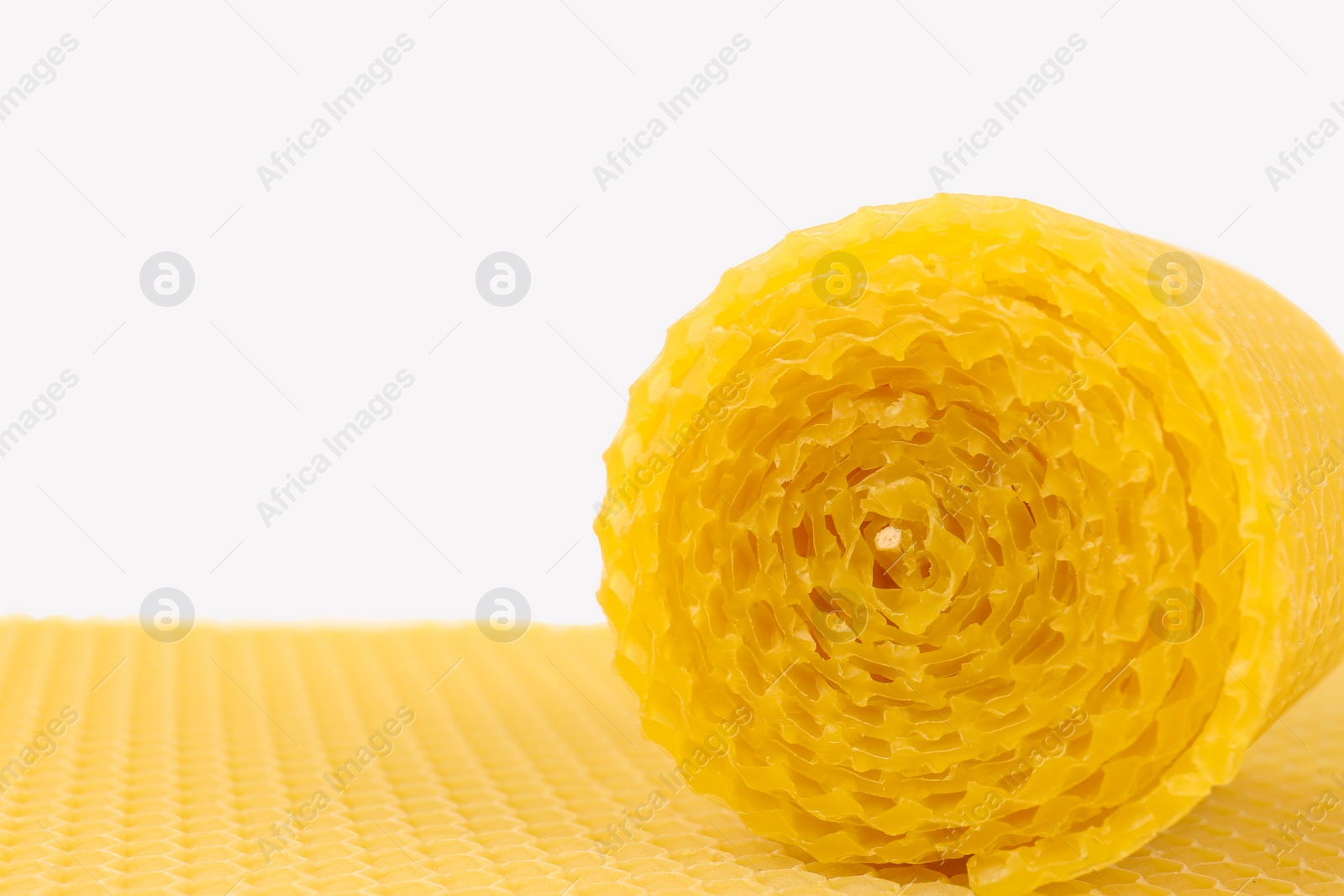 Photo of Stylish elegant beeswax candle and wax sheet on white background, closeup. Space for text