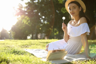 Photo of Beautiful young woman with dandelion in park on sunny day. Space for text