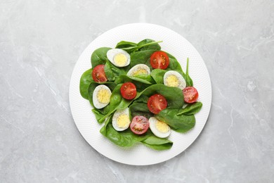 Photo of Delicious salad with boiled eggs, tomatoes and spinach on light grey table, top view