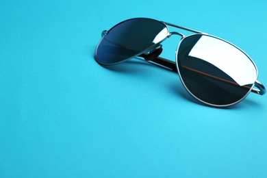 Stylish sunglasses on blue background, space for text. Fashionable accessory