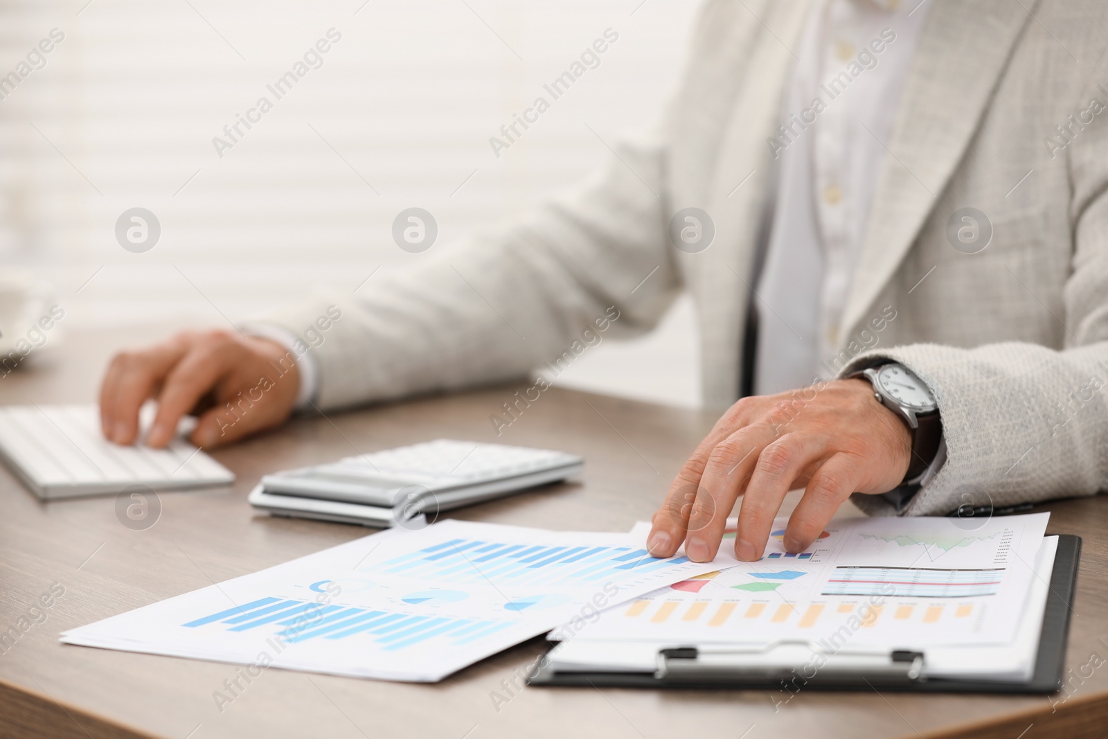 Photo of Professional accountant working at wooden desk in office, closeup