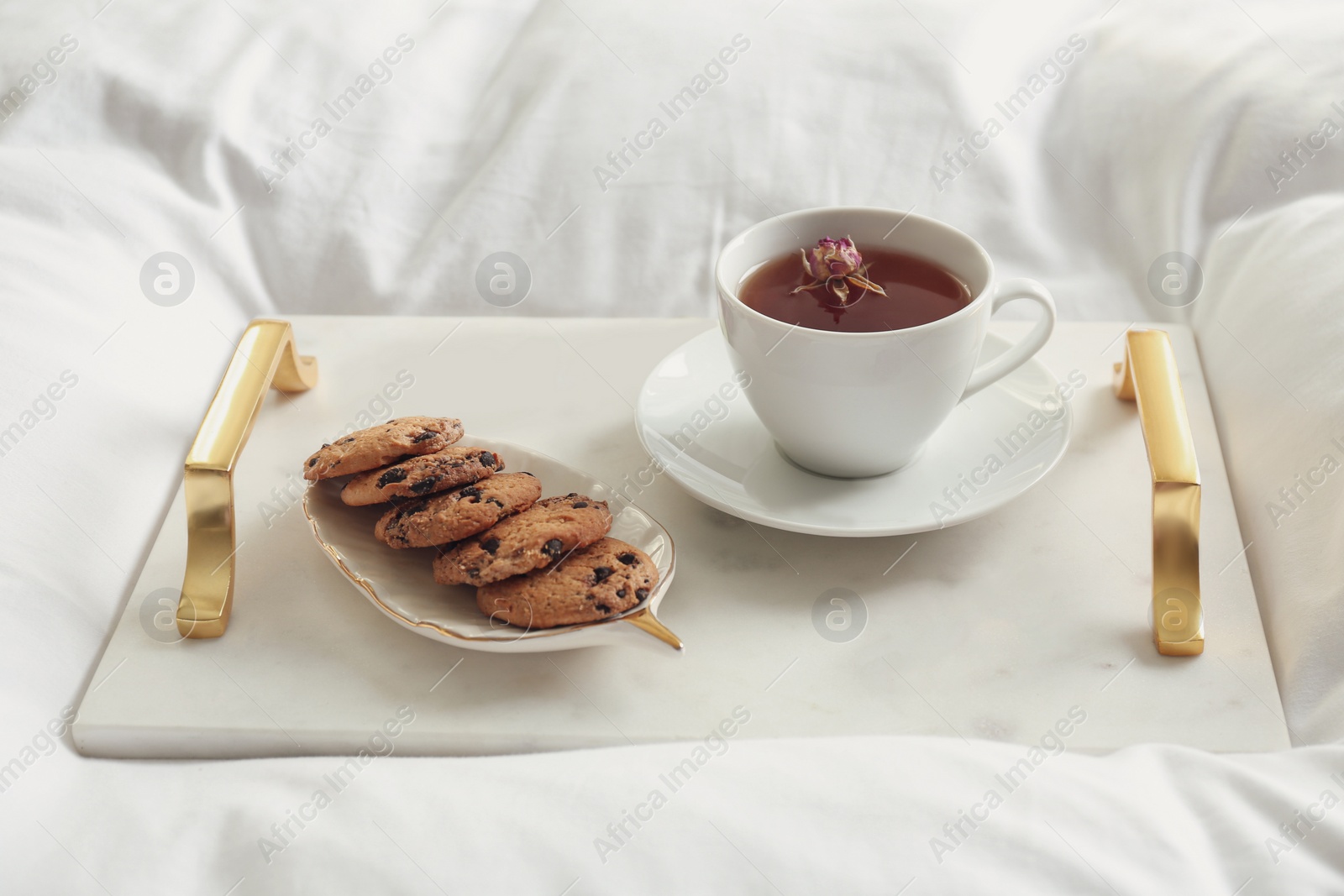 Photo of Cup of aromatic tea and cookies on soft blanket, closeup