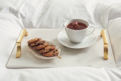 Cup of aromatic tea and cookies on soft blanket, closeup