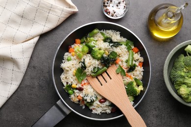 Tasty fried rice with vegetables served on black table, flat lay