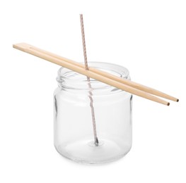 Photo of Glass jar with chopsticks as stabilizer on white background. Making homemade candle