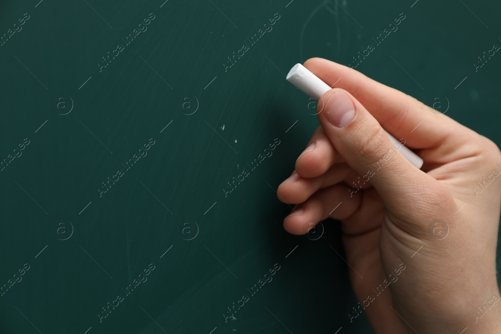 Photo of Teacher writing with chalk on green chalkboard, closeup. Space for text