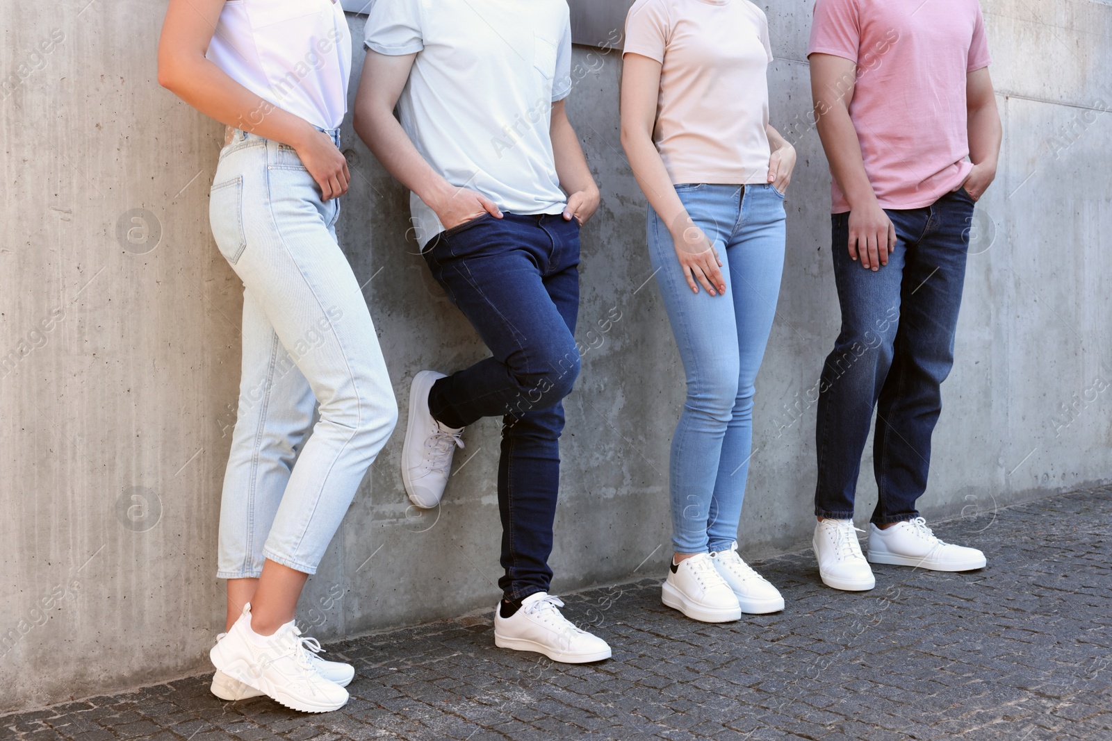 Photo of Group of people in stylish jeans near grey wall outdoors, closeup