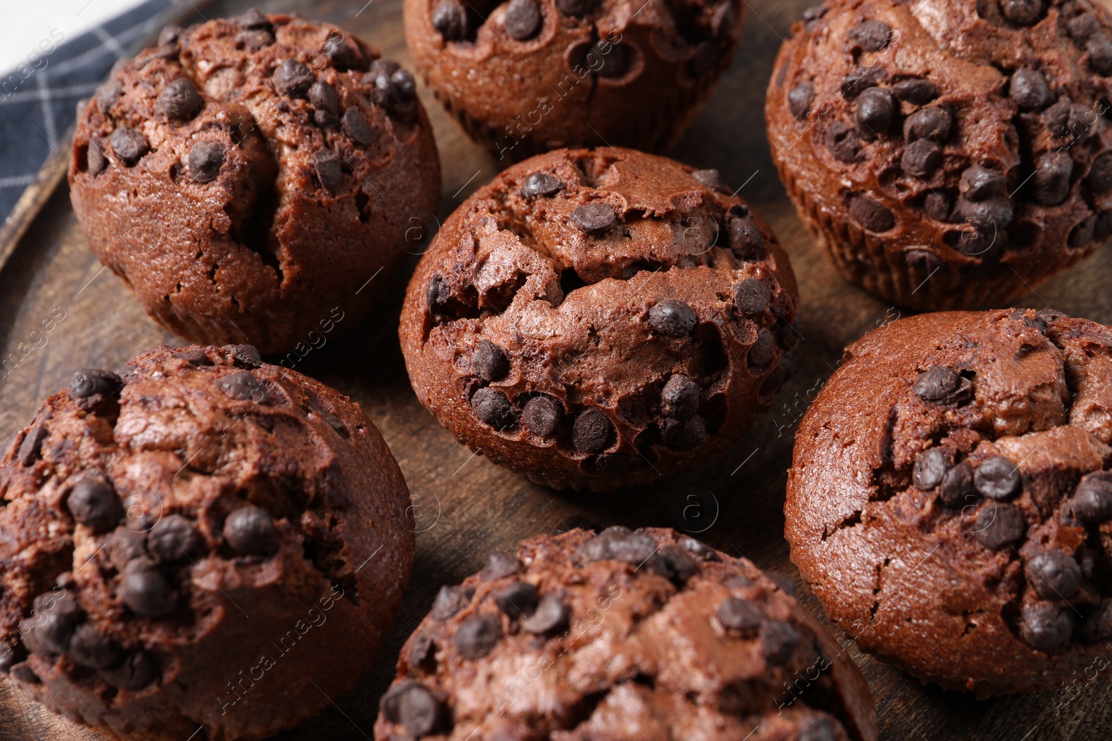 Photo of Tasty chocolate muffins on wooden board, closeup