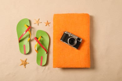 Photo of Beach towel, camera, flip flops and starfishes on sand, flat lay