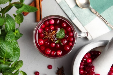 Tasty hot cranberry tea and fresh ingredients on light table, flat lay