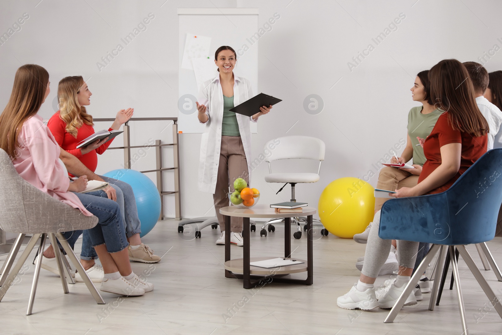 Photo of Pregnant women, men and doctor at courses for expectant parents indoors