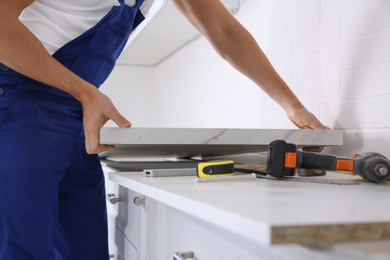 Photo of Worker installing new countertop in kitchen, closeup