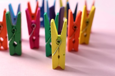 Many different colorful clothes pins on pink background. Diversity concept