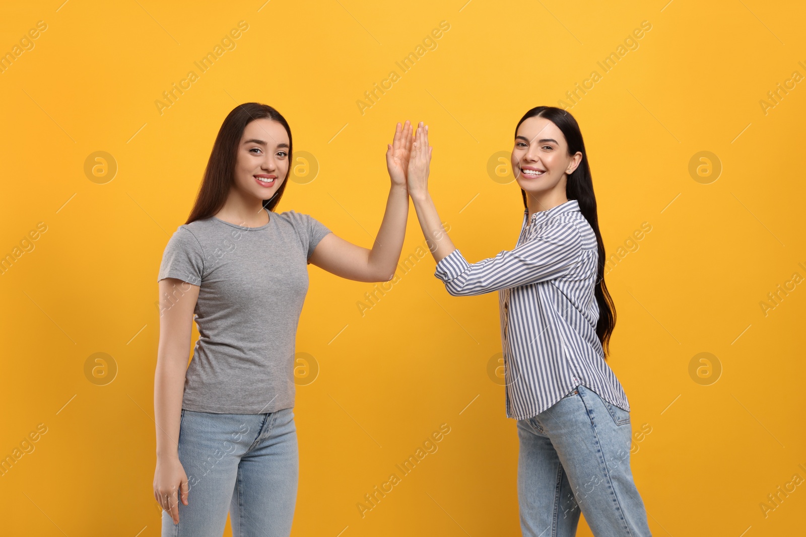 Photo of Women giving high five on orange background