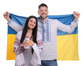 Happy couple with flag of Ukraine and traditional korovai on white background