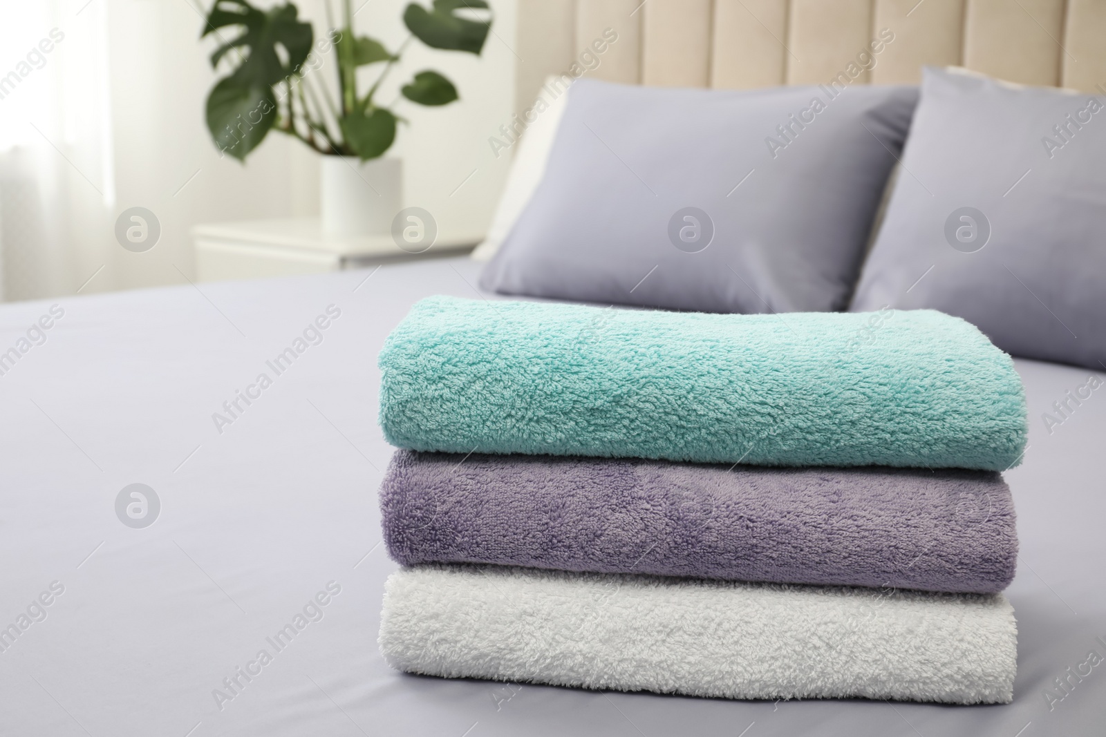 Photo of Stack of clean towels on bed indoors