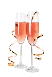 Photo of Glasses of rose champagne with gold streamer isolated on white