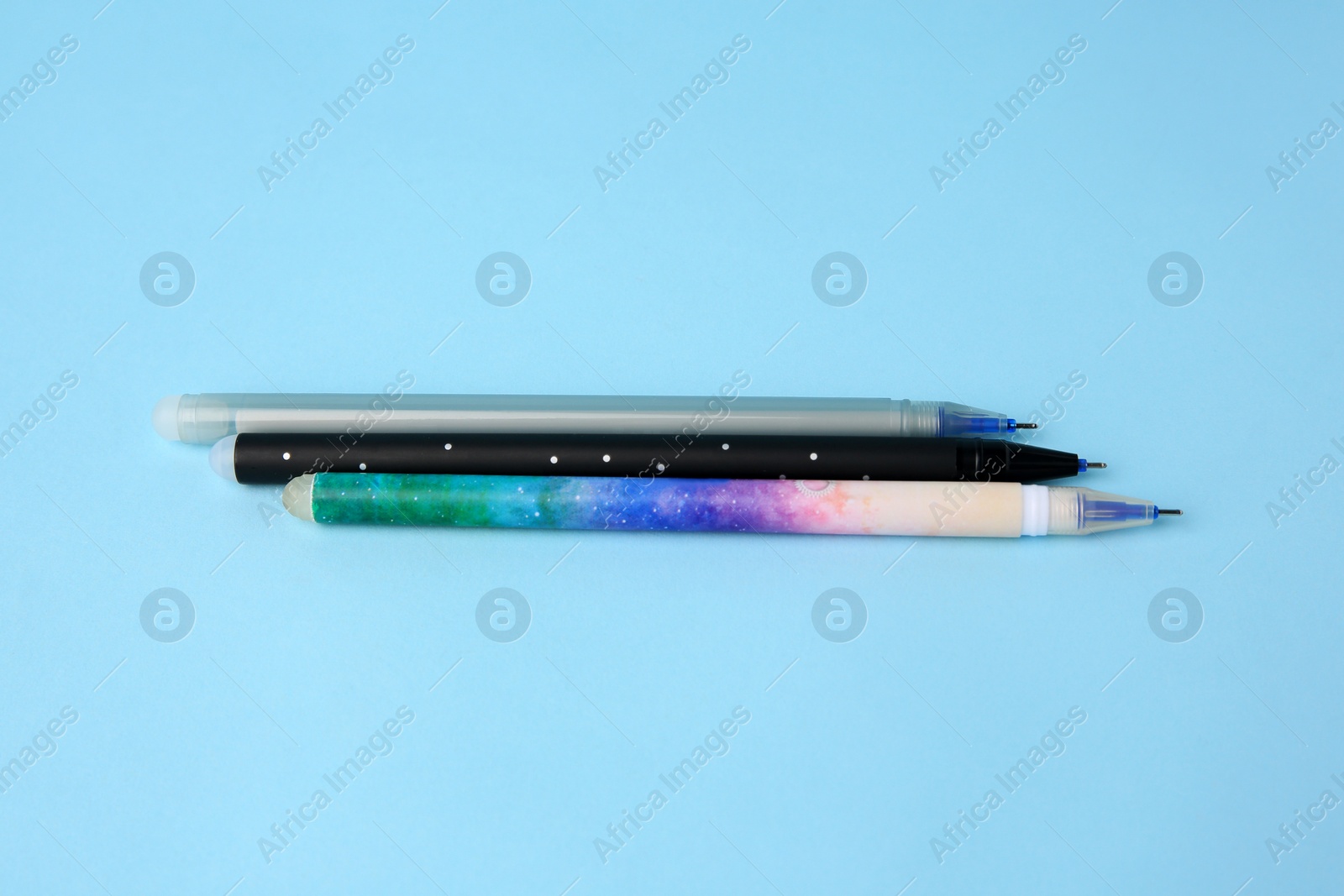Photo of Three erasable pens on light blue background, top view