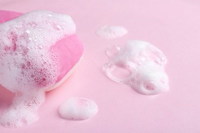 Photo of Soap bar and foam on color background, closeup view