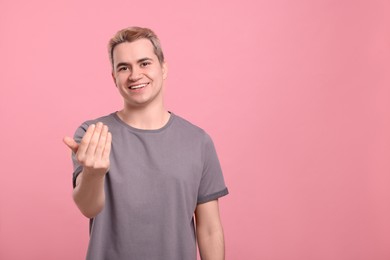 Photo of Happy man inviting to come in against pink background, space for text
