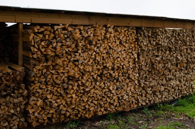 Photo of Many stacked cut firewood in outdoor warehouse