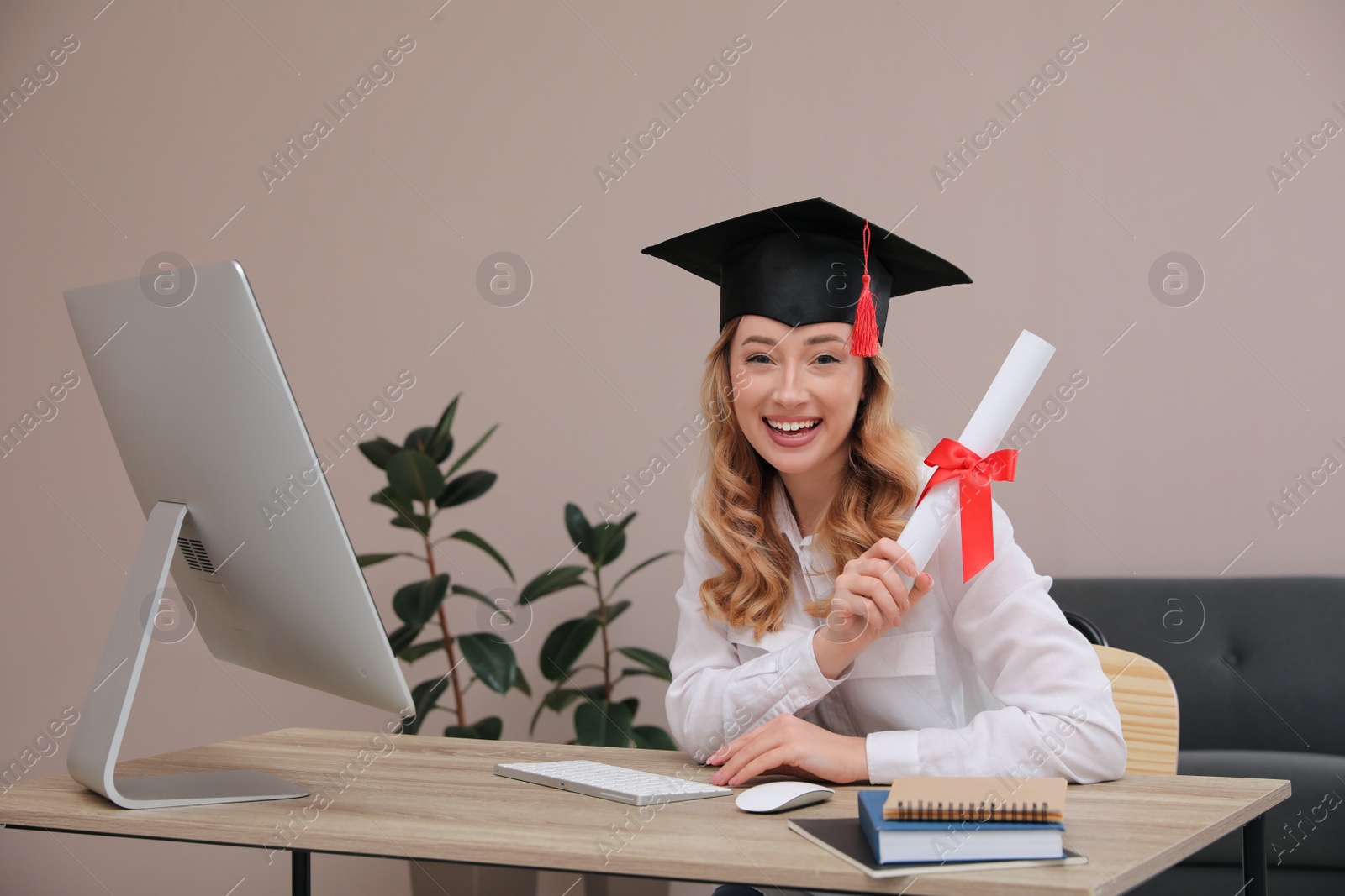 Photo of Happy student with graduation hat and diploma at workplace in office