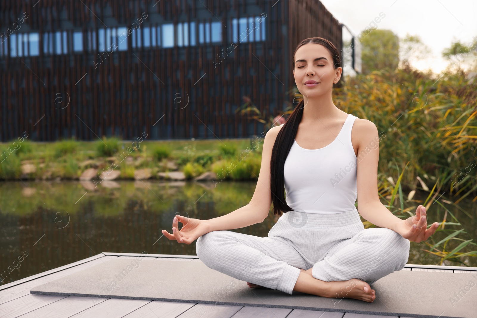 Photo of Beautiful young woman practicing Padmasana on yoga mat outdoors. Lotus pose