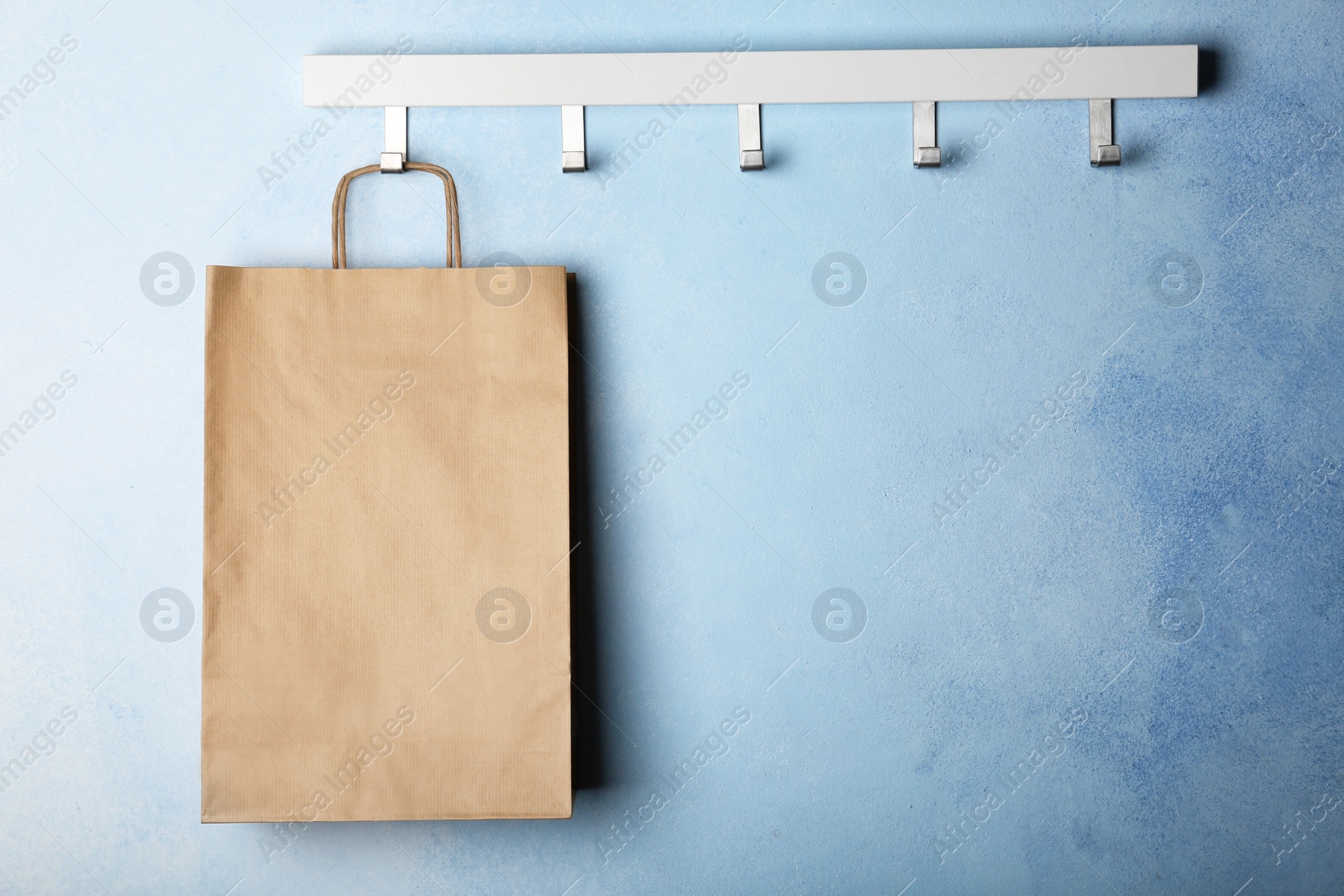 Photo of Rack with paper shopping bag on color wall