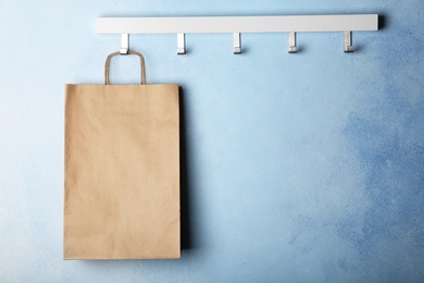 Photo of Rack with paper shopping bag on color wall