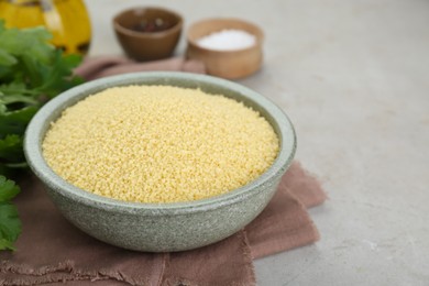 Photo of Bowl of raw couscous on light table, closeup. Space for text