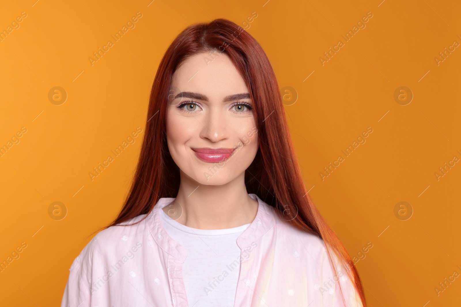 Photo of Beautiful woman with red dyed hair on orange background