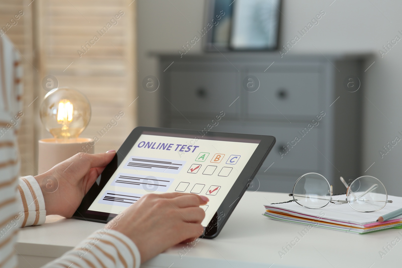 Photo of Woman taking online test on tablet at desk indoors, closeup