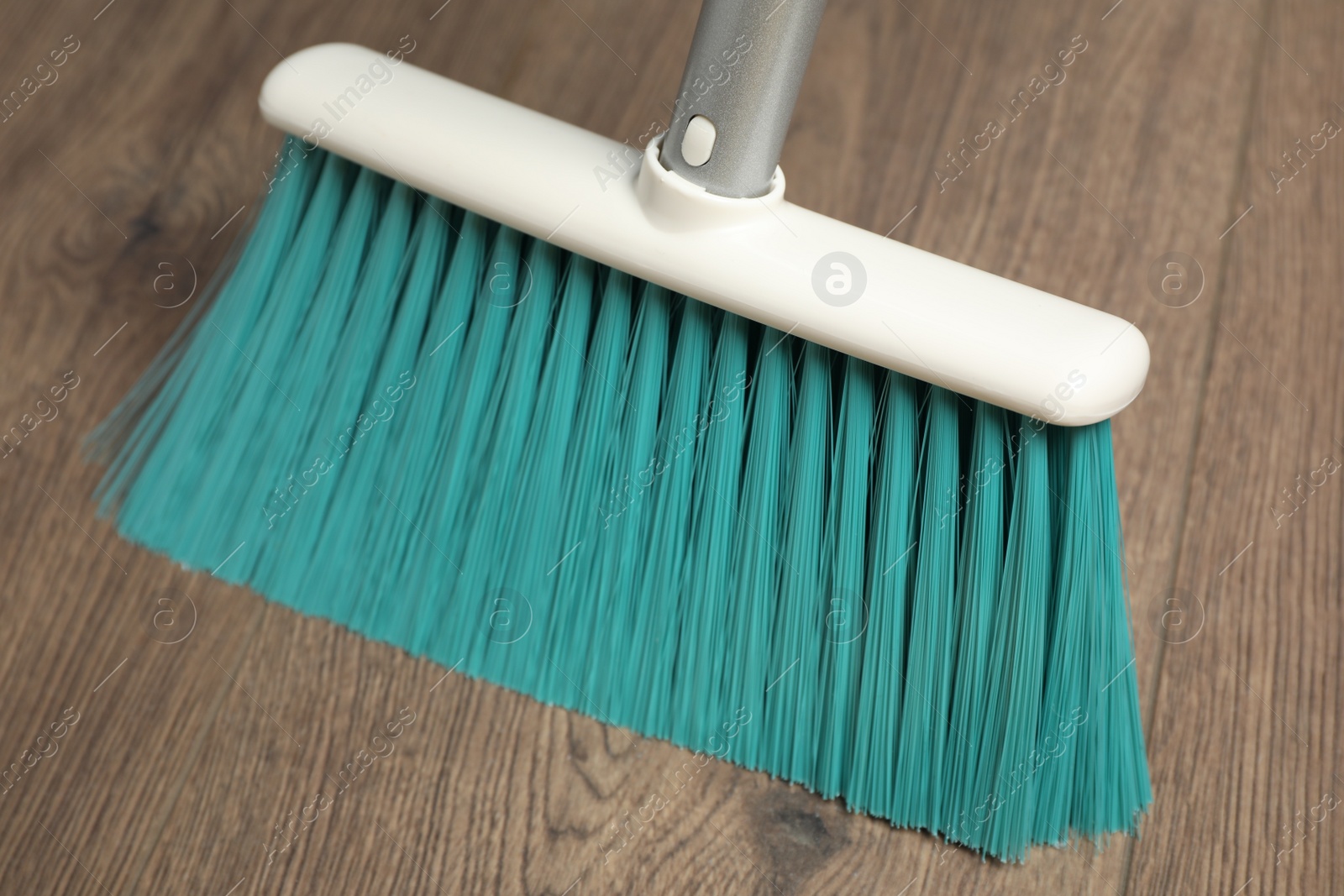 Photo of Sweeping wooden floor with plastic broom, closeup