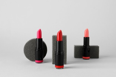 Photo of Different beautiful glossy lipsticks on light gray background