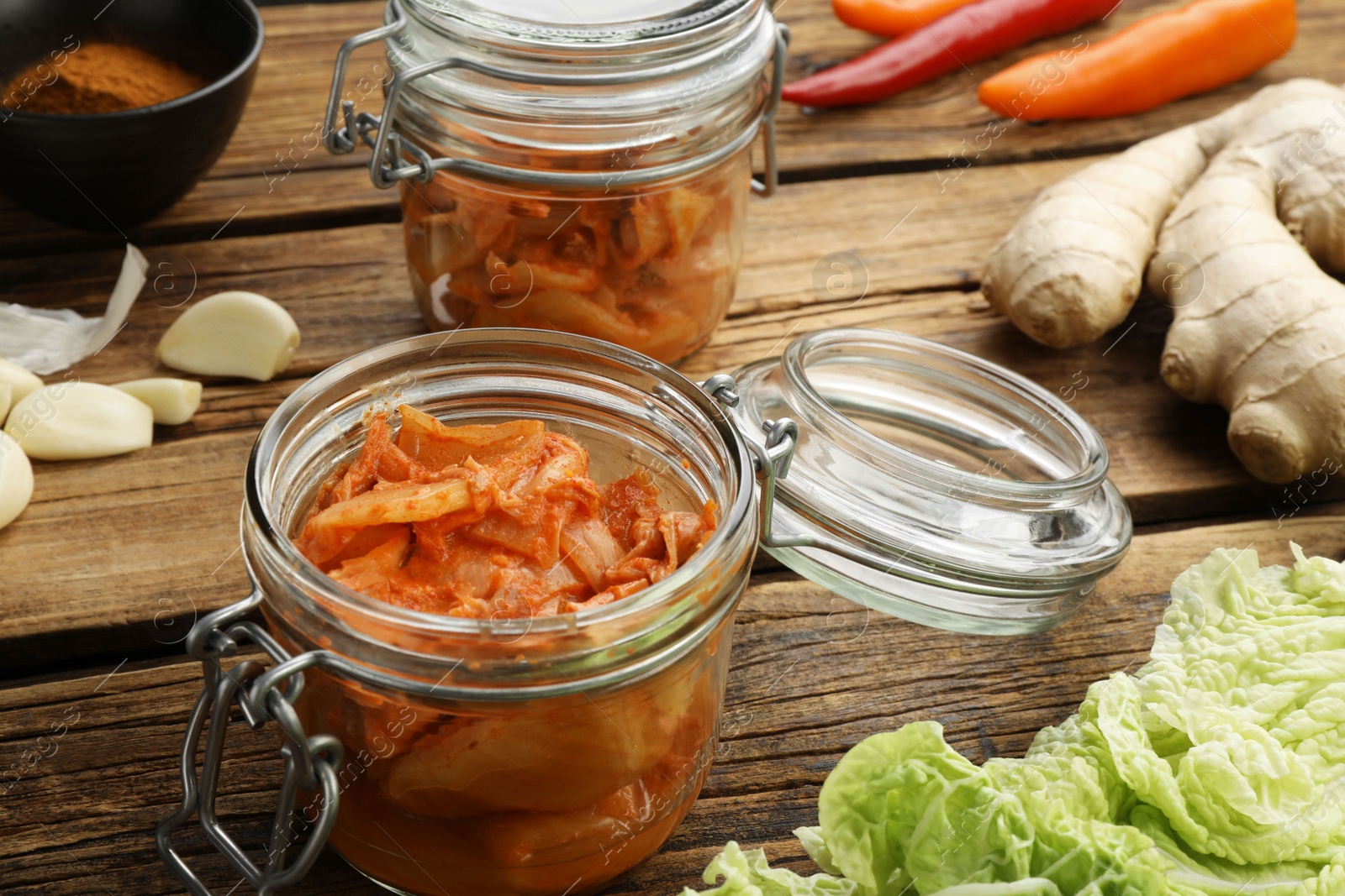 Photo of Delicious kimchi with Chinese cabbage and ingredients on wooden table, closeup