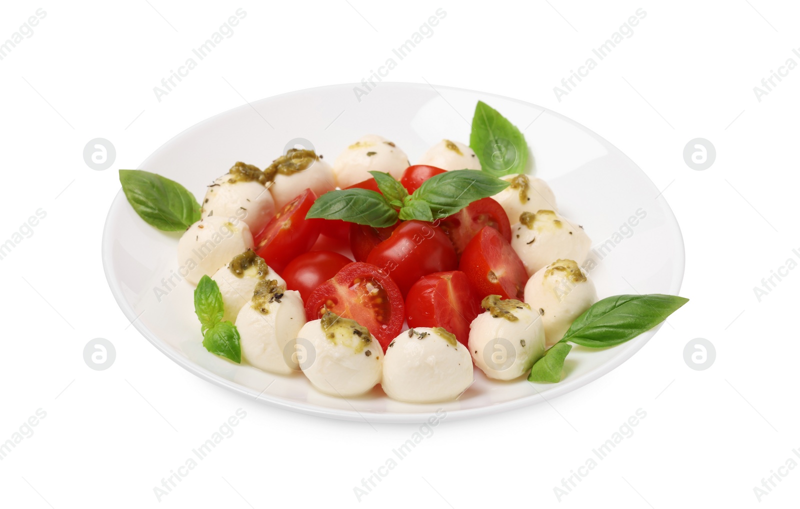 Photo of Plate of tasty Caprese salad with mozzarella, tomatoes, basil and pesto sauce isolated on white