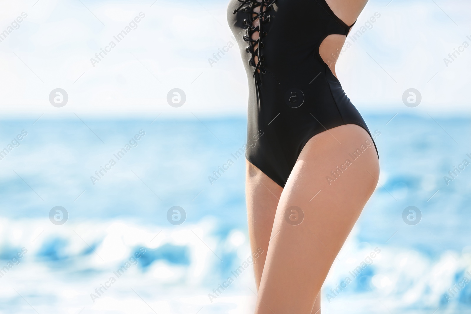 Photo of Attractive young woman in beautiful one-piece swimsuit on beach, closeup