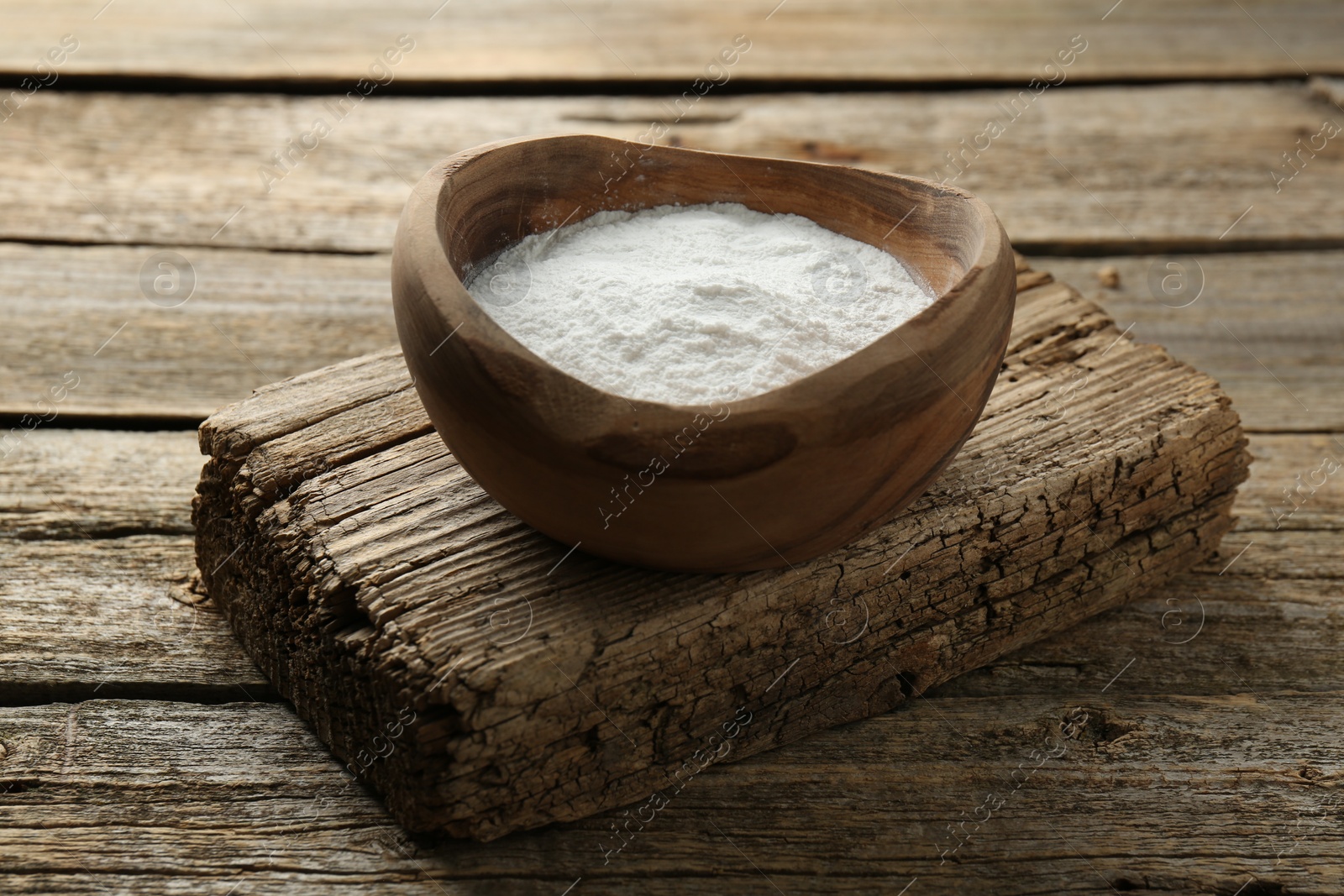 Photo of Baking powder in bowl on wooden table