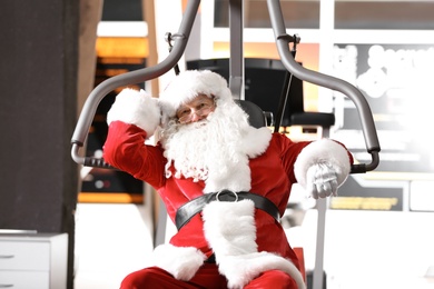 Photo of Authentic Santa Claus resting after exercise in modern gym