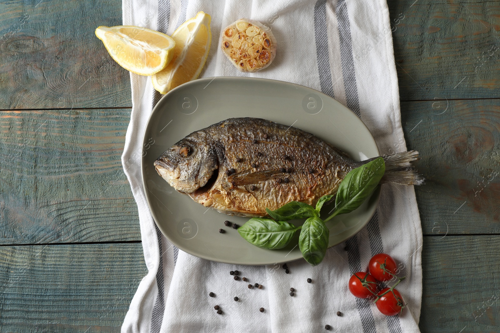 Photo of Delicious dorado fish with basil and spices served on wooden table, flat lay