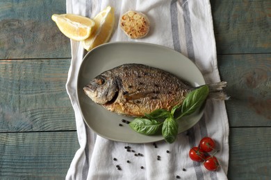 Delicious dorado fish with basil and spices served on wooden table, flat lay