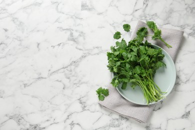 Bunch of fresh aromatic cilantro on white marble table, flat lay. Space for text