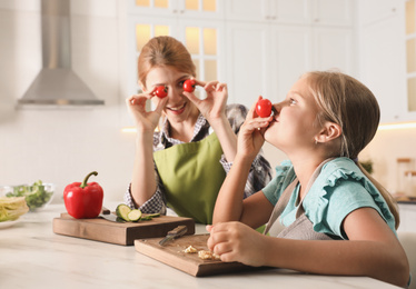 Photo of Mother and daughter cooking salad together in kitchen