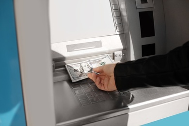 Man taking money from cash machine outdoors, closeup view