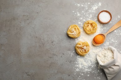 Raw noodles and ingredients on grey table, flat lay. Space for text