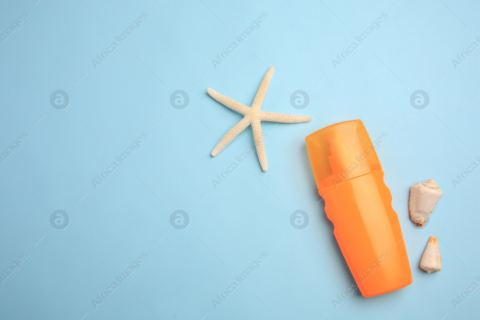 Photo of Bottle of sunscreen, starfish and seashells on light blue background, flat lay. Space for text
