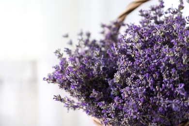 Photo of Fresh lavender flowers in basket on blurred background, closeup. Space for text