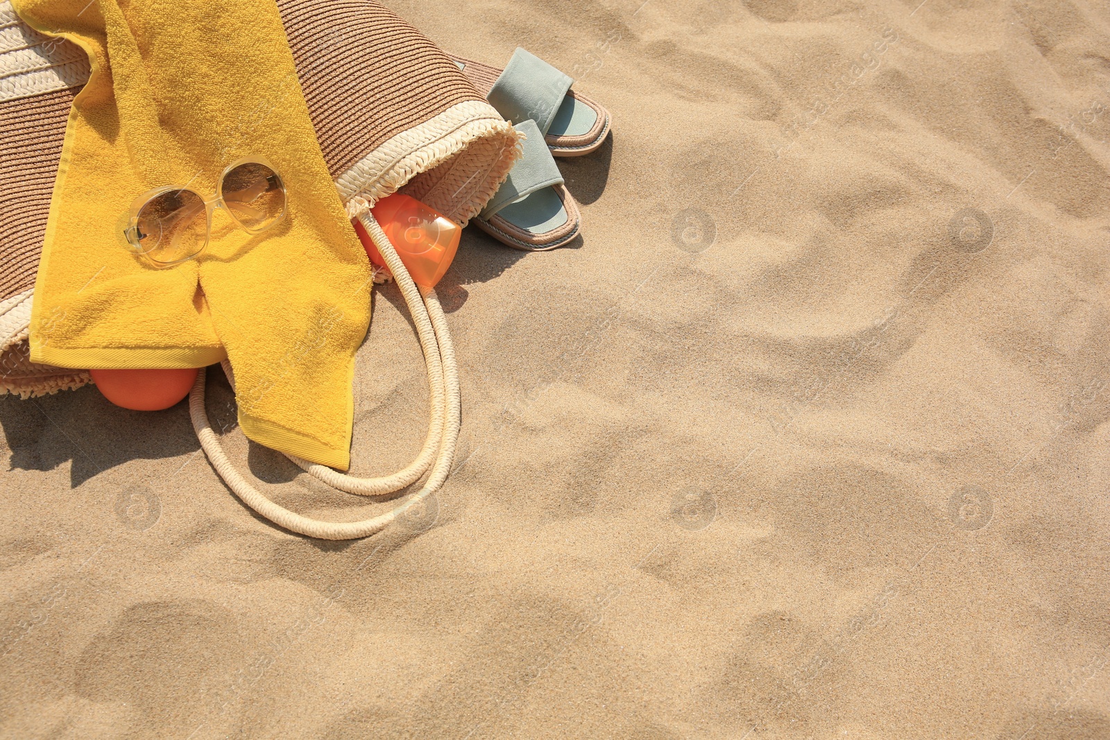 Photo of Beach bag, sunglasses and other accessories on sand, top view. Space for text